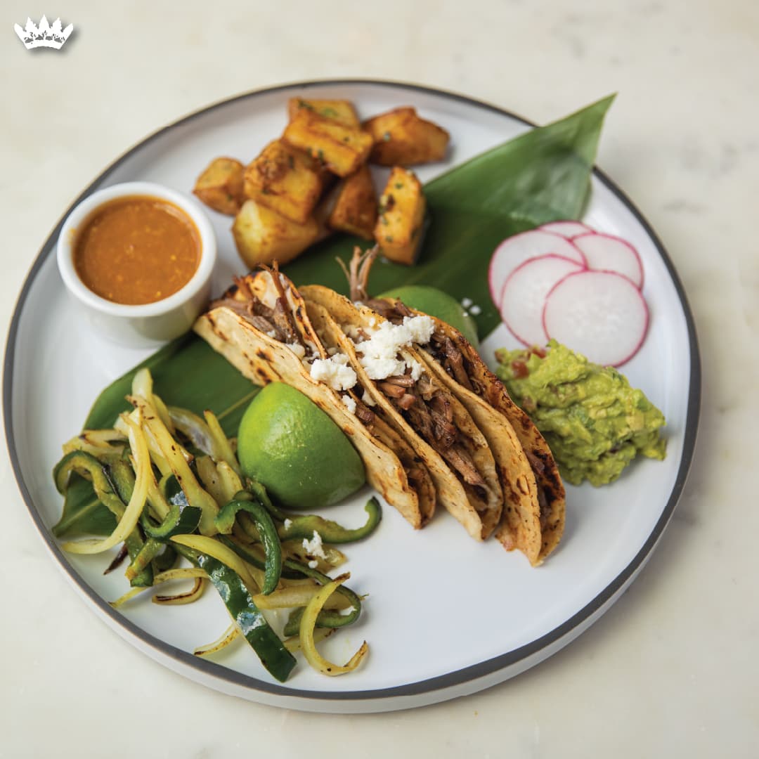 Brisket tacos on warm corn tortillas with guacamole, asadero, salsa roja, grilled poblano and onion, finished with queso fresco.